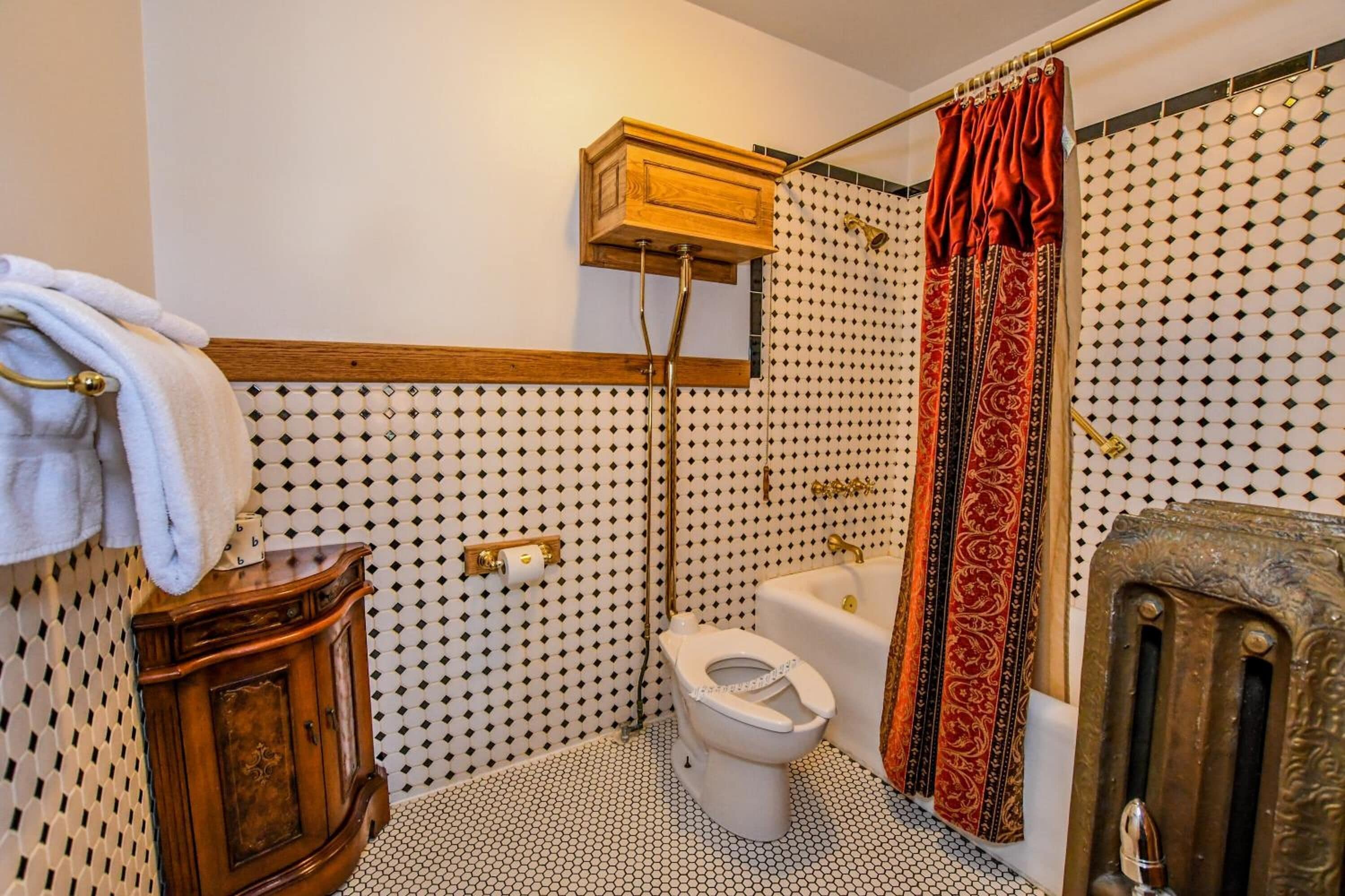A bathroom with a toilet, bathtub, and shower. There is a towel rack with a towel on it.
