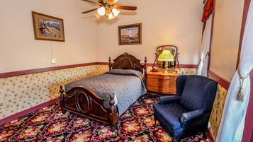 A bedroom with a wooden bed, a chair, a dresser, and two framed pictures on the wall.