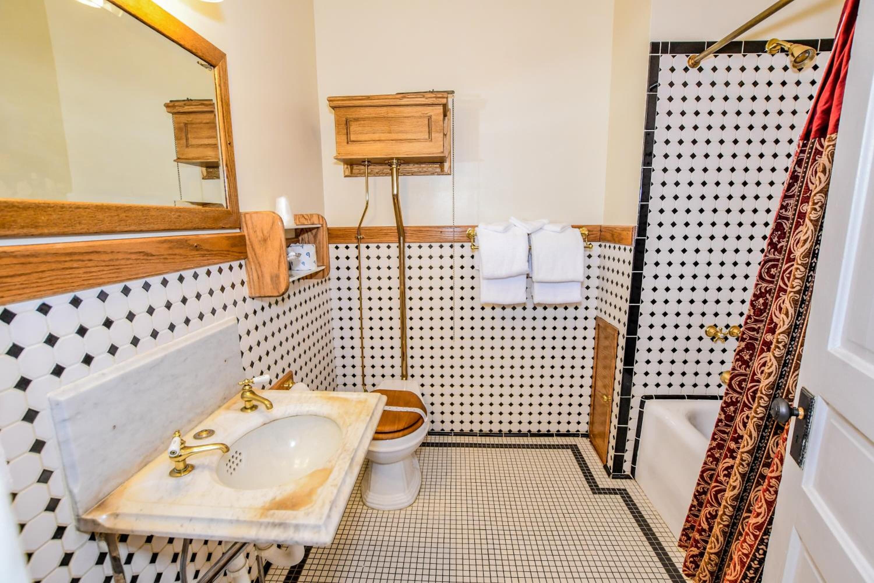 Un baño con tocador de madera, un lavamanos blanco, inodoro y cortina de ducha.