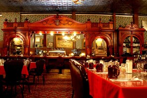 Restaurante com arcos de madeira, toalhas de mesa vermelhas e um candelabro.
