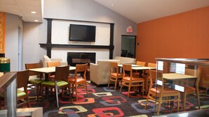 A hotel lobby with a fireplace, multiple seating areas, and a television mounted on the wall. - Days Inn by Wyndham Woodbury Long Island (Woodbury)