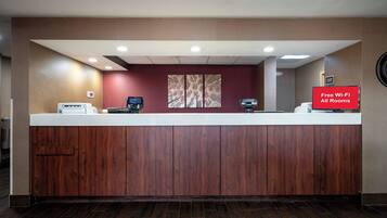 A reception desk with a digital screen, a 'Free Wi-Fi All Rooms' sign, and a 'Manager On Duty' sign.