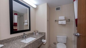 A bathroom with a granite countertop, a sink, a mirror, a toilet, and a shower curtain.