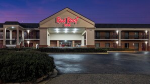 A Red Roof Inn with a prominent sign, a parking lot, and a well-lit entrance.