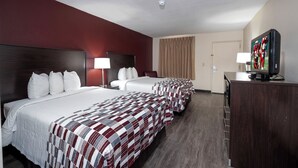 A hotel room with three beds, a television, and a dresser.