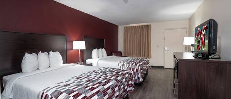 Habitación de hotel con tres camas, televisión y cómoda.