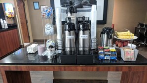 A coffee station with multiple coffee makers, sugar and creamer dispensers, and a variety of coffee pods.