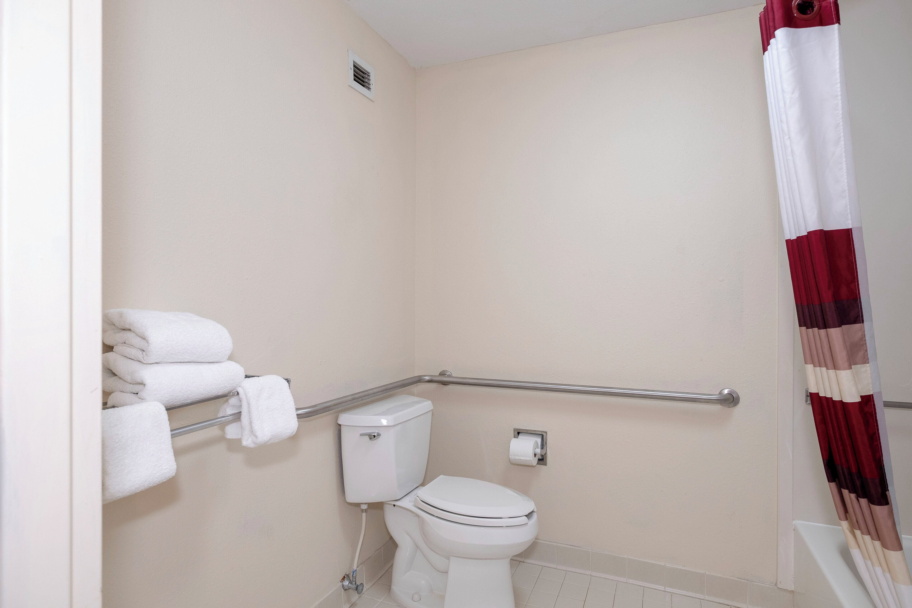 A bathroom with a toilet, a towel rack, and a shower curtain.
