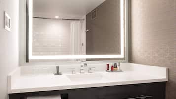 A modern bathroom with a large mirror, white sink, and a towel rack.