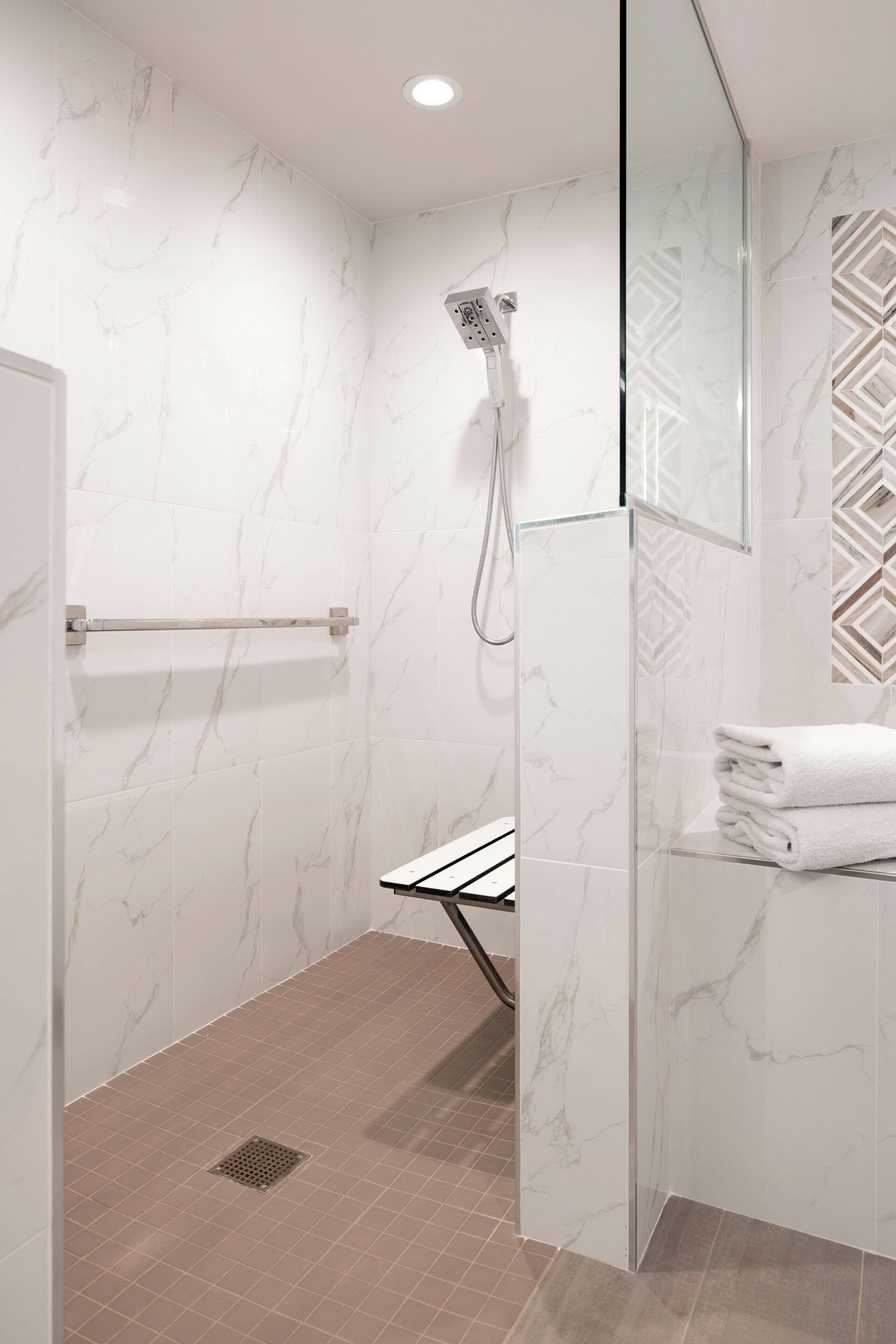 A modern bathroom with a glass shower enclosure, a towel rack, and a mirror.