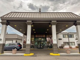 Un edificio con acceso cubierto, columnas y estacionamiento.