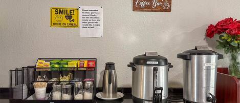Een koffiehoek met koffiezetapparaat, heetwaterdispenser en een bord met de tekst 'Coffee Bar'.