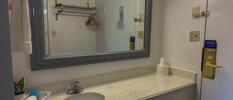 A bathroom with a large mirror, a sink, a towel rack, and a hand dryer.