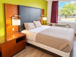A hotel room with a bed, bedside tables, lamps, and a window with curtains.