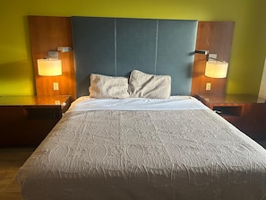 A hotel room with a large bed, two bedside lamps, and a headboard.