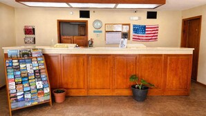 Een receptiebalie met een houten kast, een potplant, een wandklok, een prikbord en een Amerikaanse vlag.