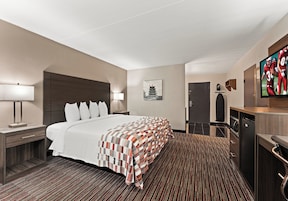 Una habitación de hotel con una cama grande, un escritorio con lámpara, un televisor y un armario.