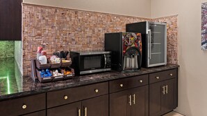 Eine Küchenzeile mit Steinrückwand, einem Kühlschrank, einer Mikrowelle und einer Kaffeemaschine.