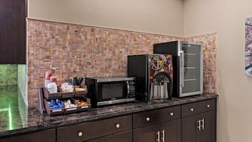 Una cocina con protector de piedra, una cafetera y un refrigerador.