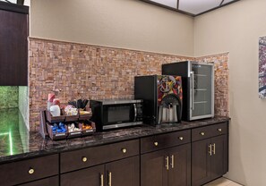 A kitchen with a stone backsplash, a coffee machine, and a refrigerator. - Red Roof Inn Reading (Reading)