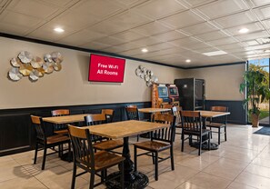 A restaurant with multiple tables and chairs, a television screen displaying 'Free Wi-Fi All Rooms', and a sign for 'Peninsula'. - Red Roof Inn Reading (Reading)