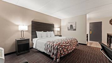 A hotel room with a bed, bedside tables, a lamp, a painting, and a door.