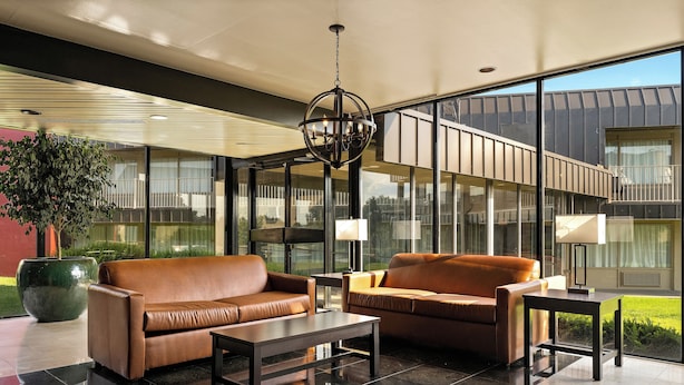 A modern lounge area with leather sofas, a coffee table, and a chandelier. - Red Roof Inn Reading (Reading)