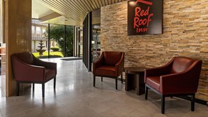 Eine Red Roof Inn Lobby mit modernem Design, ausgestattet mit Ledersesseln, einer Steinwand und einem großen Fenster mit Blick ins Freie.