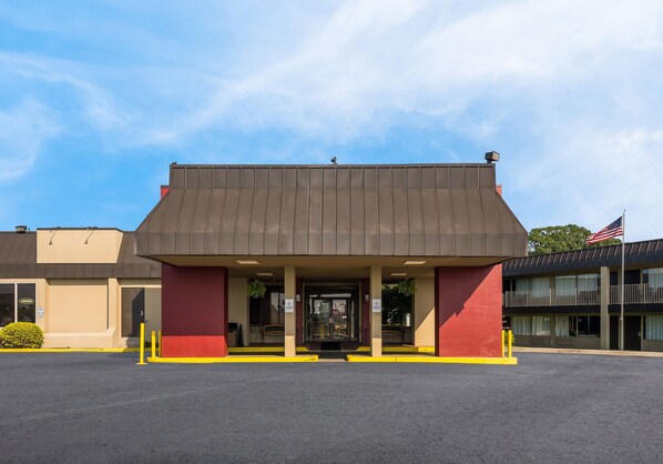 Standalone building with a flat roof and double doors, set amidst a parking lot and trees.
