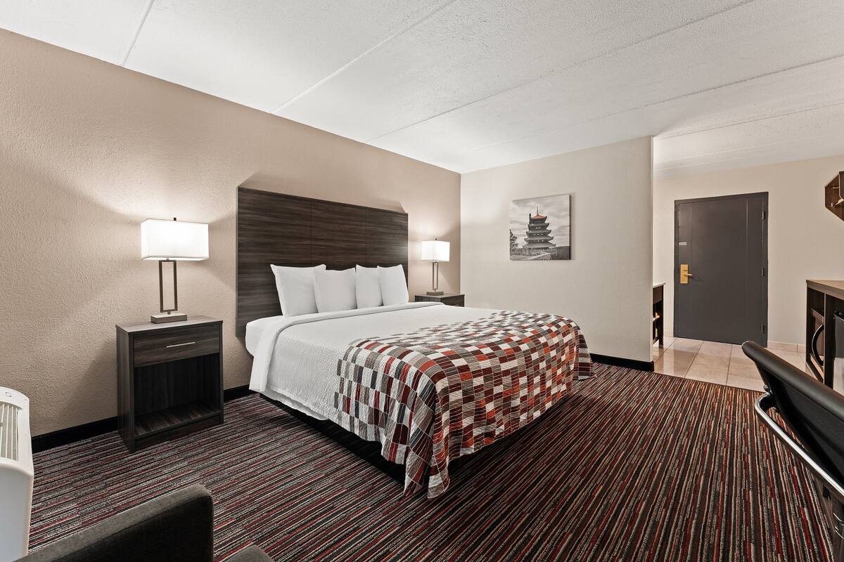 Una habitación de hotel con una cama grande, una mesita de noche, un escritorio y una silla.