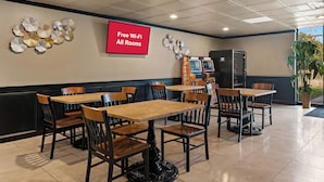 A restaurant with tables and chairs, a red sign indicating free Wi-Fi, and a wall decoration. - Red Roof Inn Reading (Reading)