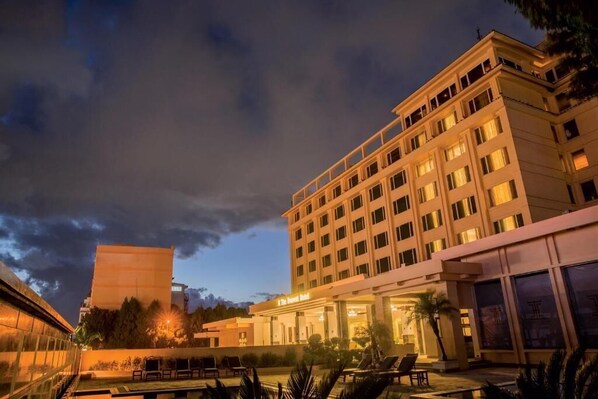 Un hotel con piscina, varias plantas y una entrada bien iluminada.