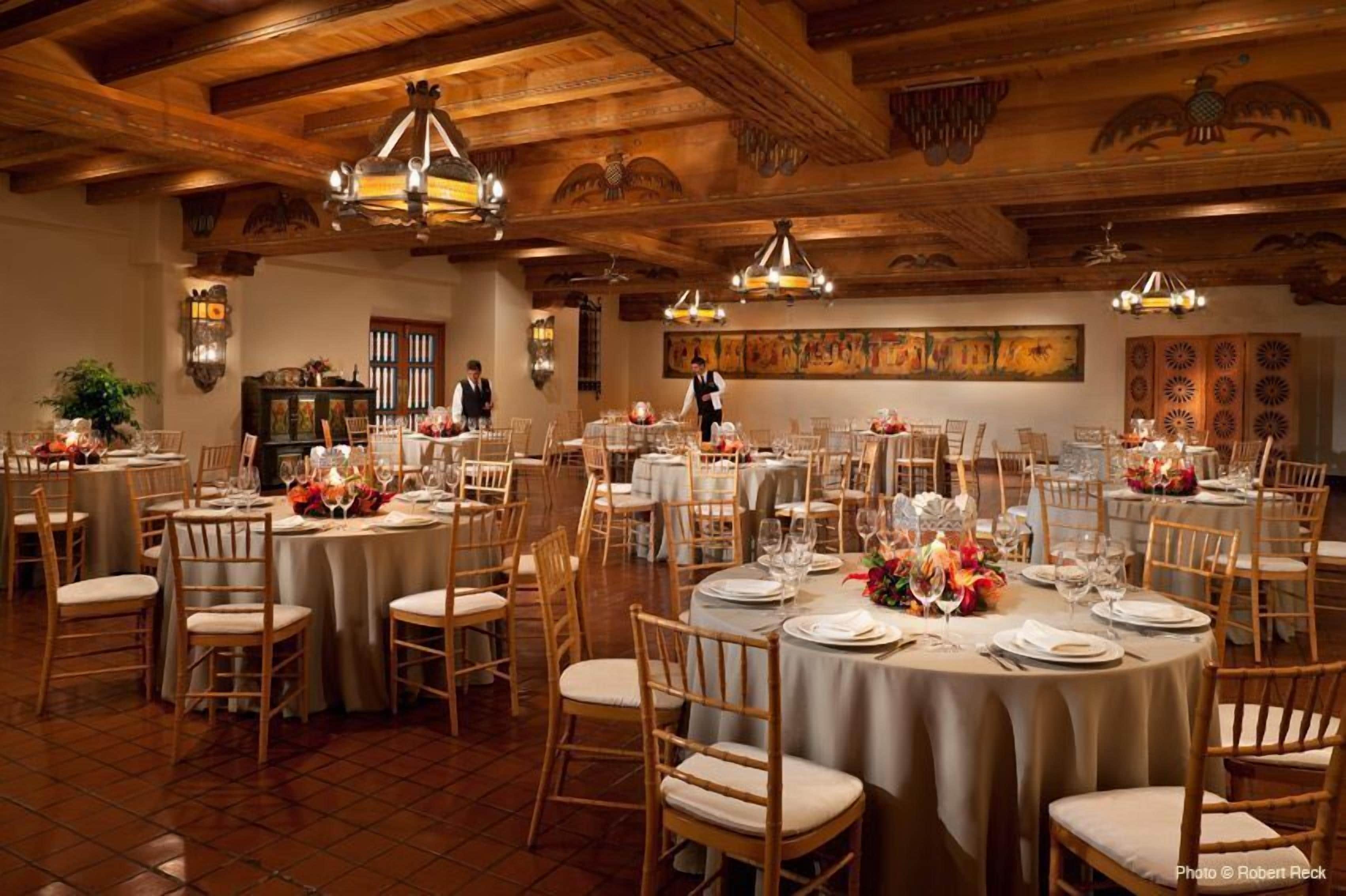 Un restaurant avec des tables rondes, des chaises en bois et un plafond haut avec des poutres en bois.