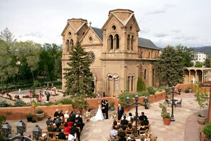 A wedding ceremony outdoors with a historic church in the background. - La Fonda on the Plaza (Santa Fe)