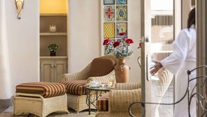 A cozy room with wicker furniture, a vase with red flowers, and a decorative wall panel. - La Fonda on the Plaza (Santa Fe)