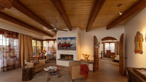 A spacious living room with wooden beams, a fireplace, and a dining area with a table and chairs. - La Fonda on the Plaza (Santa Fe)