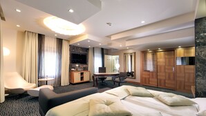 Une chambre d’hôtel avec un grand lit, un bureau, une chaise, un canapé et une télévision.