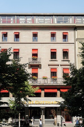 A building with multiple windows, some with red awnings, and a sign that reads 'HOTEL'.