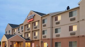 Een Fairfield Inn & Suites Marriott hotel met een modern design, met een centrale ingang, meerdere ramen en een parkeerplaats.