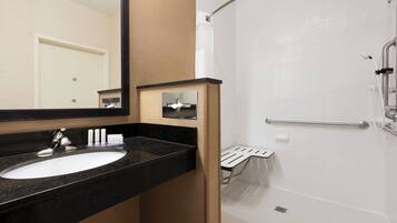 A bathroom with a sink, mirror, and shower.