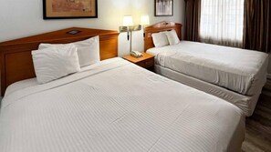 A hotel room with two beds, a nightstand with a lamp, and a framed picture on the wall. - Motel 6 San Francisco, CA - Lombard Street (San Francisco)