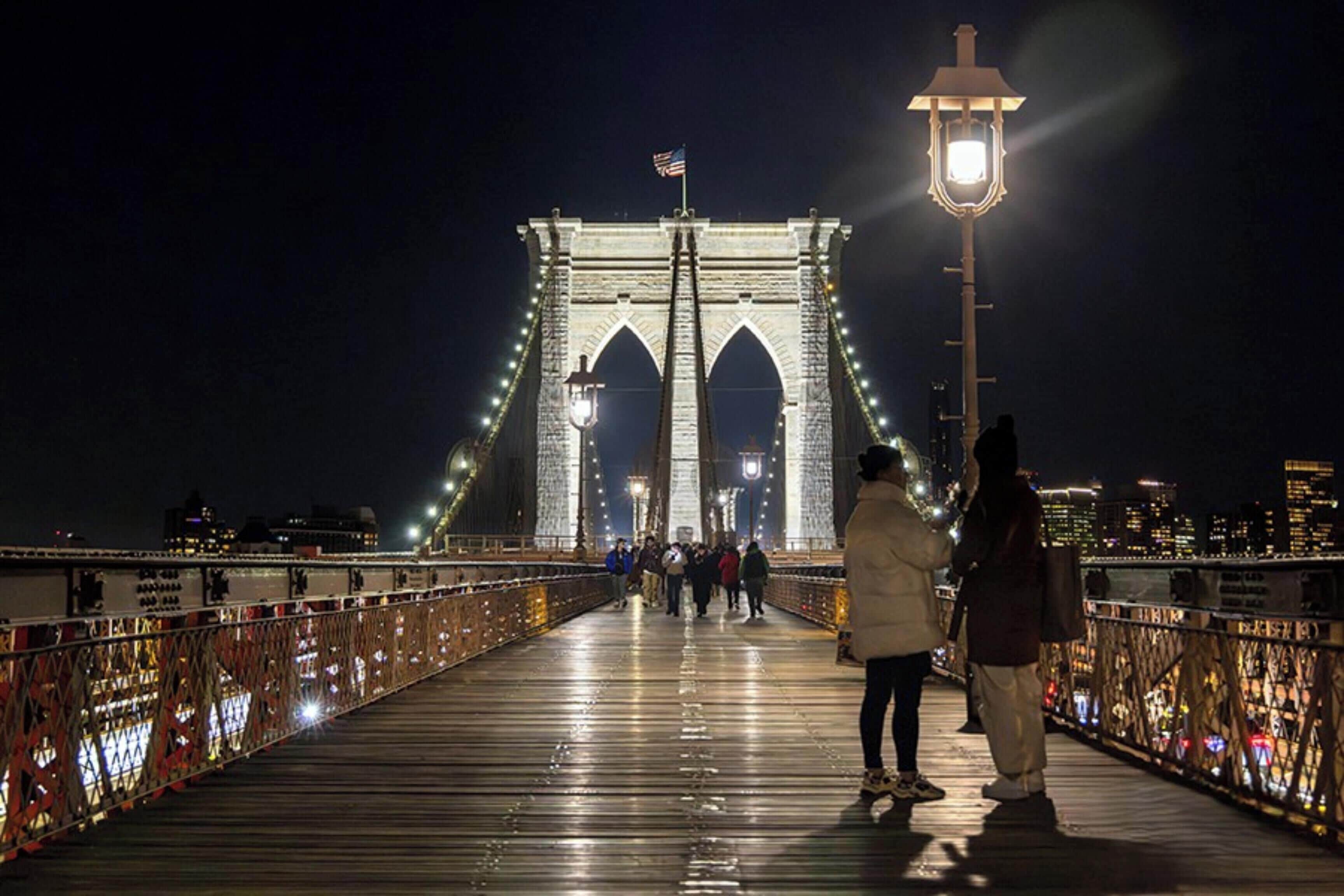 A bridge with a pedestrian walkway, an American flag, and a street lamp.