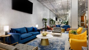 A modern lobby with a blue sofa, a gold coffee table, and yellow armchairs. - OYO Times Square (New York)