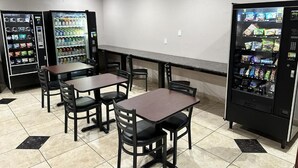 A restaurant area with tables and chairs, vending machines, and a counter. - Super 8 by Wyndham Mesa Downtown Near Convention Center (Mesa)