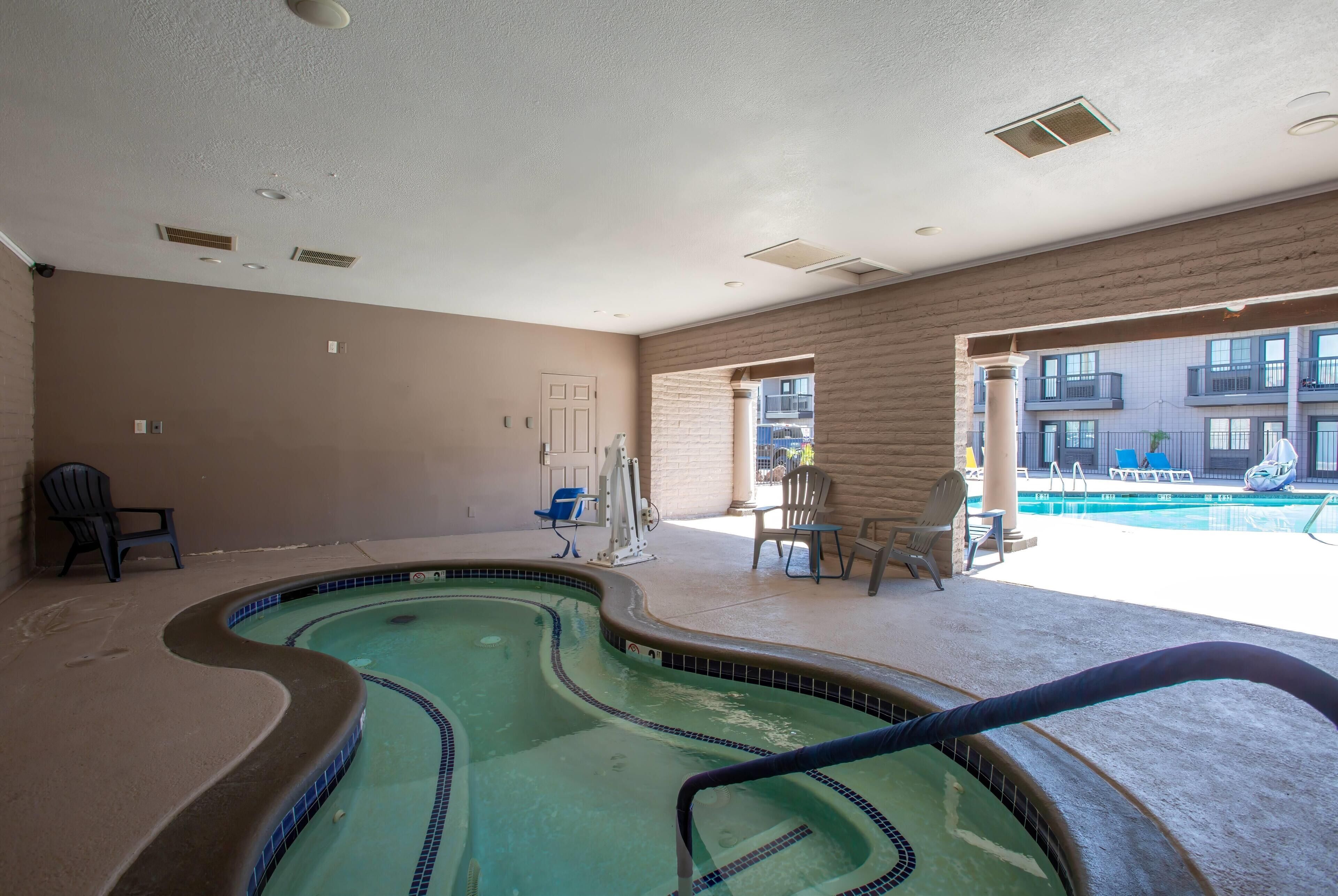 A swimming pool area with a curved design, a lounge chair, and a door leading to an outdoor balcony.