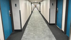 A long, narrow hotel corridor with doors on both sides, a carpeted floor, and a ceiling with recessed lighting. - Super 8 by Wyndham Mesa Downtown Near Convention Center (Mesa)