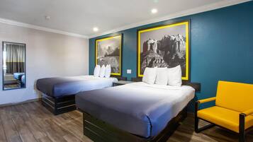 Quarto de hotel com duas camas, um espelho, uma cadeira amarela e duas fotografias grandes a preto e branco nas paredes.