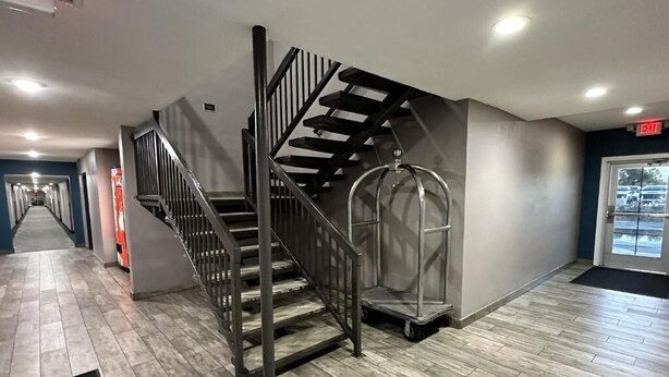 A modern interior with a metal staircase, a metal railing, and a black mat at the entrance. - Super 8 by Wyndham Mesa Downtown Near Convention Center (Mesa)