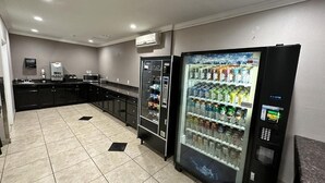 A hotel kitchen with black cabinets, a microwave, a coffee machine, and a refrigerator. - Super 8 by Wyndham Mesa Downtown Near Convention Center (Mesa)