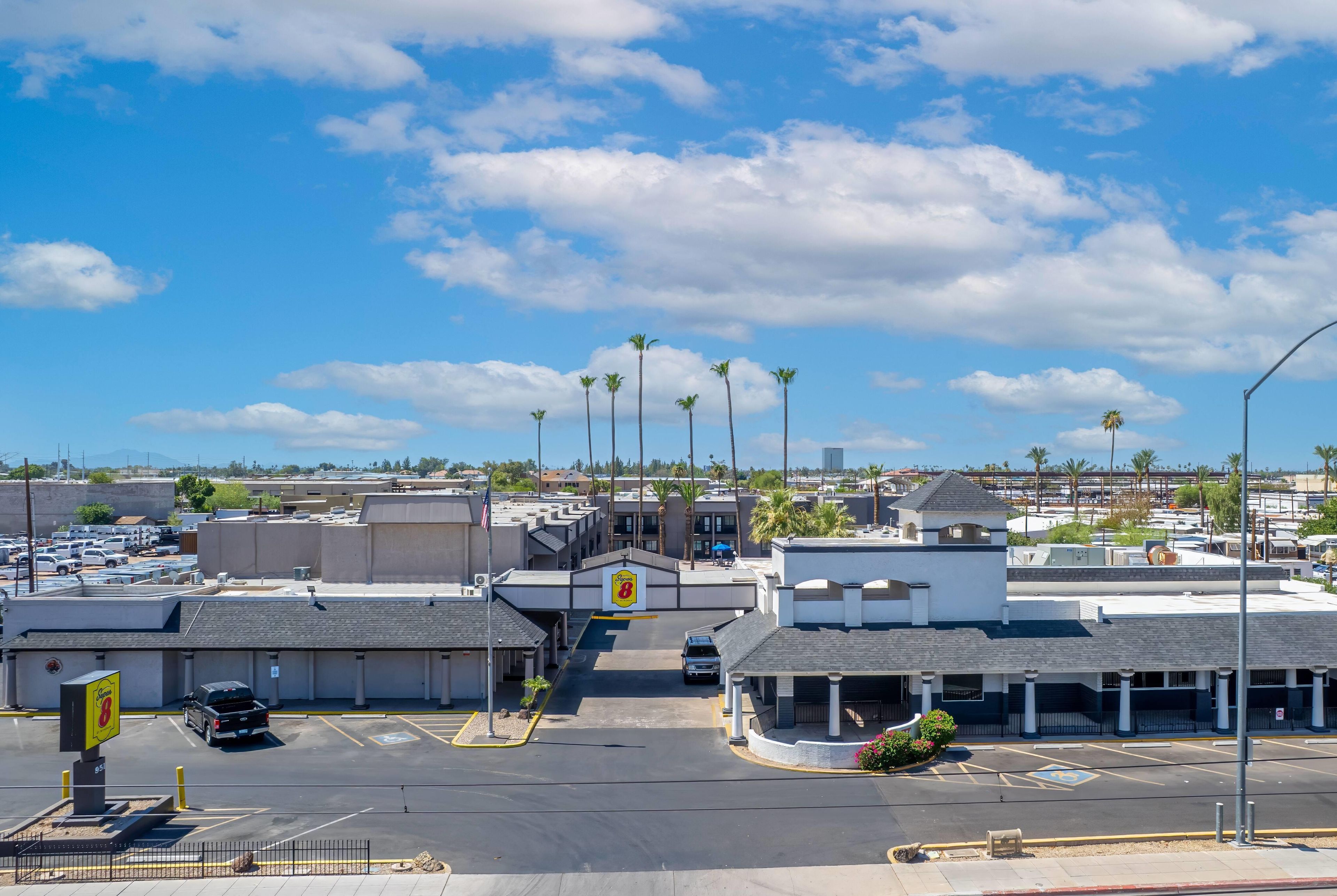 A parking lot with multiple parking spaces, a clear sky, and a few palm trees.